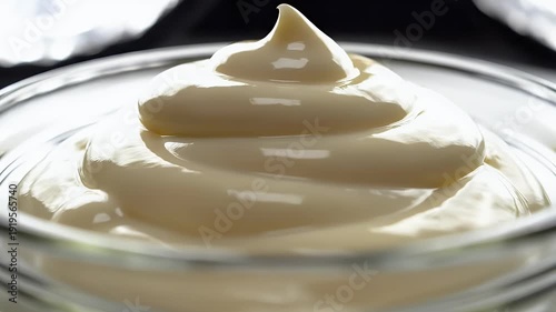 Creamy white sauce swirl in glass bowl against neutral background