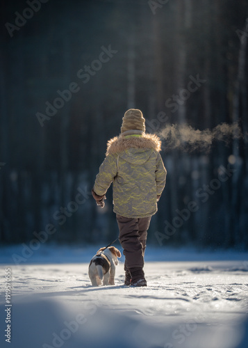 child walking in winter park with dog