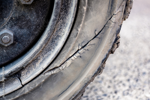 Close-up of a damaged tire showing visible cracks and wear, highlighting issues of tire maintenance and safety on vehicles.