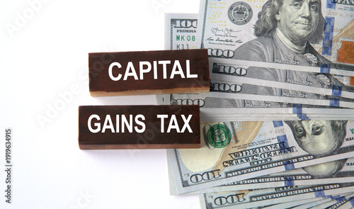 CAPITAL GAINS TAX - inscriptions on wooden blocks on a white background with images of banknotes.