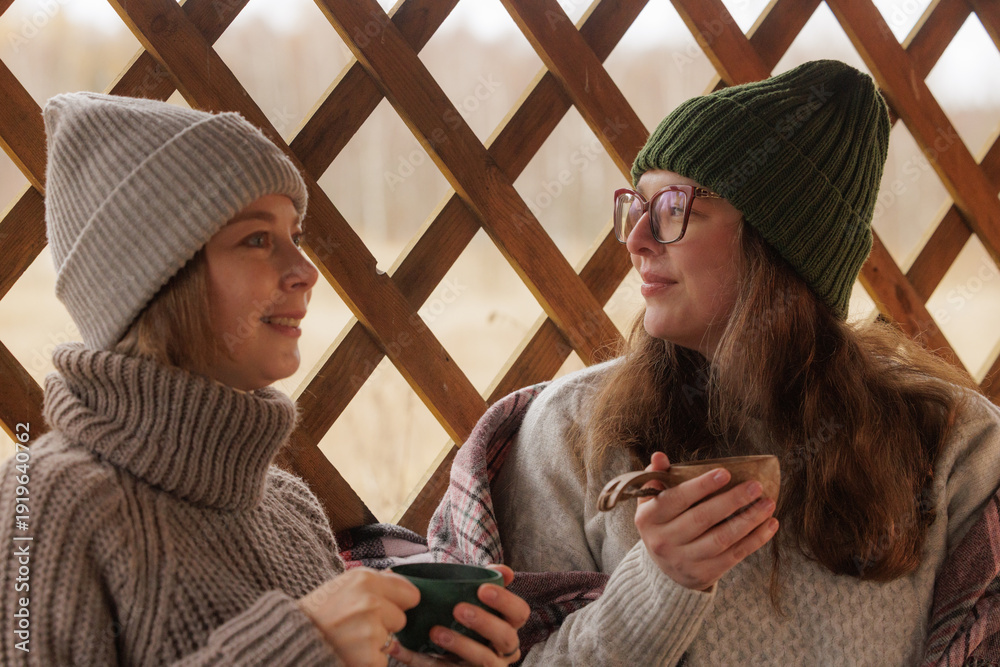 Εκτύπωση καμβά Two friends share warm drinks and laughter on a cozy winter afternoon by the win