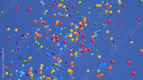 Colorful party balloons floating in blue sky - celebration, freedom and joy concept