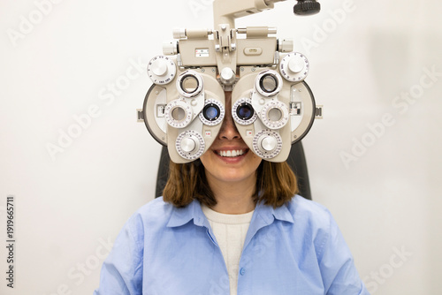 Woman undergoing eye test with phoropter in optician clinic