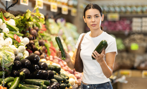 Bild auf Leinwand Young woman shopping in vegetable store and buy zucchini