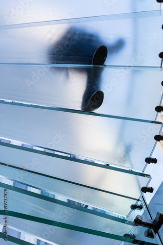 Silhouettes of people walking on glass stairs in modern architecture