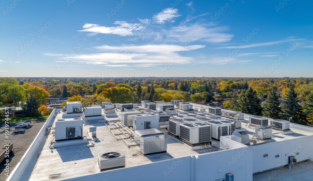 Obraz premium White flat roof with multiple air conditioning units and ventilation systems on commercial building under blue sky