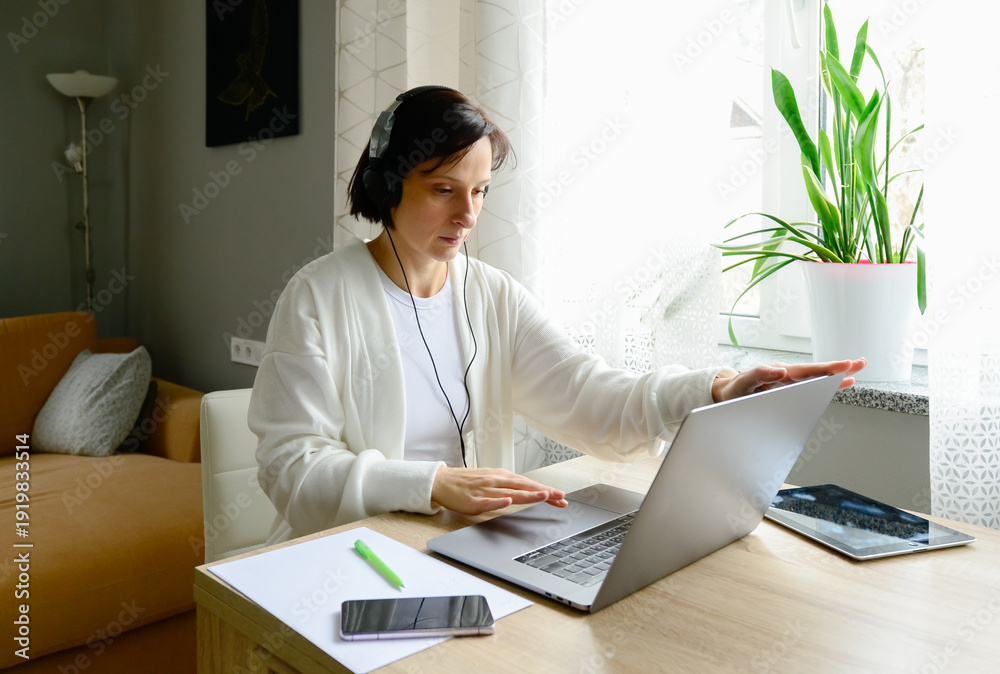 Fototapeta premium A business professional woman works remotely from home using electronic gadgets and devices.