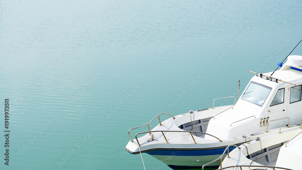 Fototapeta premium High angle view of a white yacht docked on calm turquoise water, minimalist style