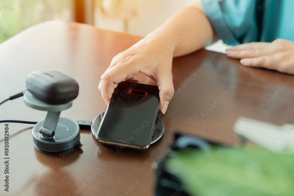 Fototapeta premium Woman placed smartphone on a wireless charger next to an earphones charging
