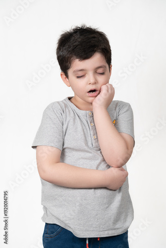 Young Boy with Closed Eyes and Hand on Cheek, Appearing Sleepy or in Discomfort
