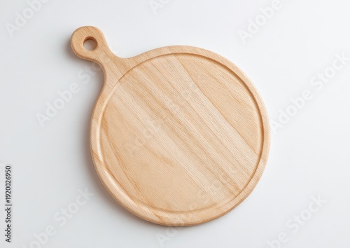 Overhead shot of a clean, round wooden cutting board with a handle on a white surface
