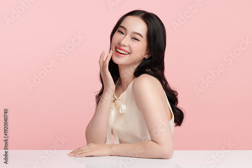 A beautiful young Asian woman with clean, fresh skin against a pink background. Skincare, facial treatment, cosmetology, beauty, and spa. An elegant portrait of an Asian woman.