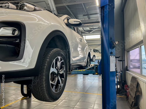 Картината върху платно Car undergoing maintenance on a hydraulic lift in a modern auto repair workshop