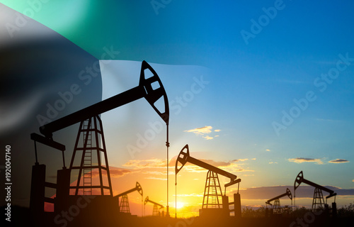 Silhouette of oil pump jacks with Kuwait flag against the sunset or sunrise. Kuwait Oil Industry concept