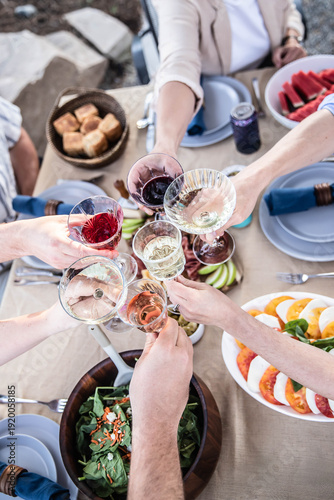 Friends raising glasses toasting at outdoor celebration dinner