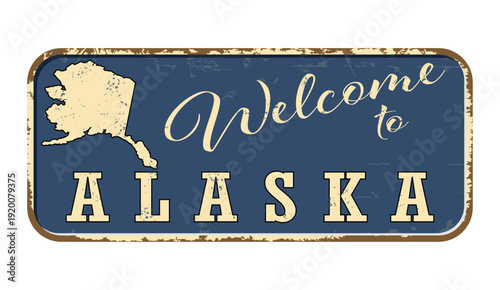 Welcome to Alaska. A worn blue plaque with the name and outline of the state. Welcome inscription on the road sign