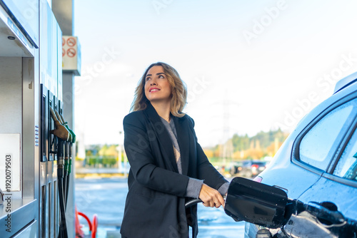Tableau sur toile Woman refueling car with gasoline at gas station