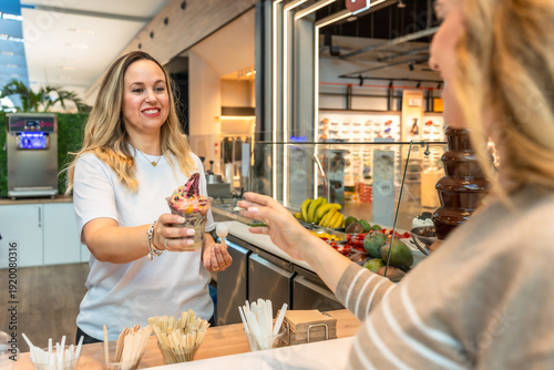 Canvastavla Woman serving acai bowl with frozen yogurt in shop