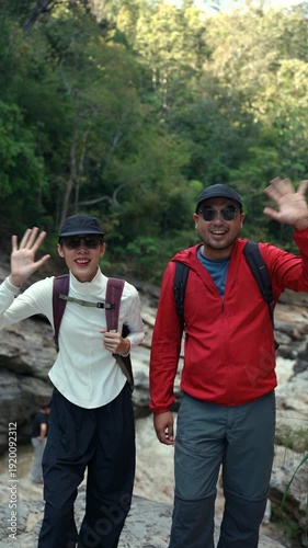 Vertical shot cheerful young asian couple hiking with backpack in mountain outdoor adventure on holiday vacation, hiking lifestyle in nature exploration and freedom journey for mental health wellness.