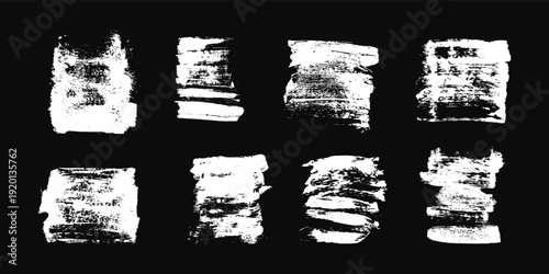 White grunge brush strokes on a black background. Abstract textured ink elements for layering in graphic design and art projects.