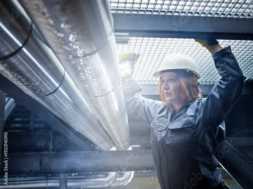 Craftswoman wearing hard hat working at pipe