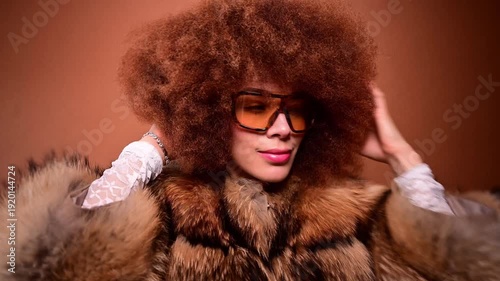 Stylish woman with afro dancing in a fur coat