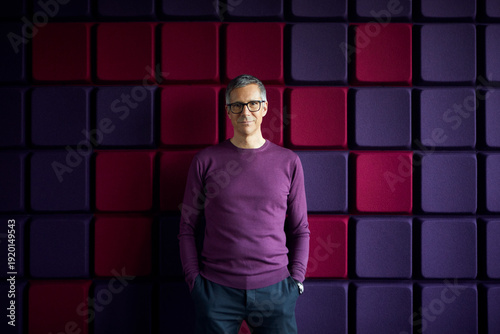 Portrait of confident businessman at a noise reduction wall in office
