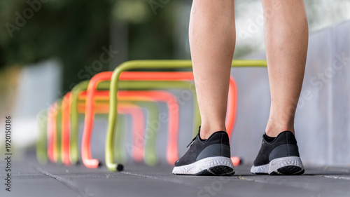 Legs of young woman standing by small hurdle