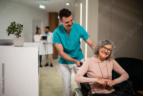 Fotografie Nurse assisting smiling senior woman in wheelchair
