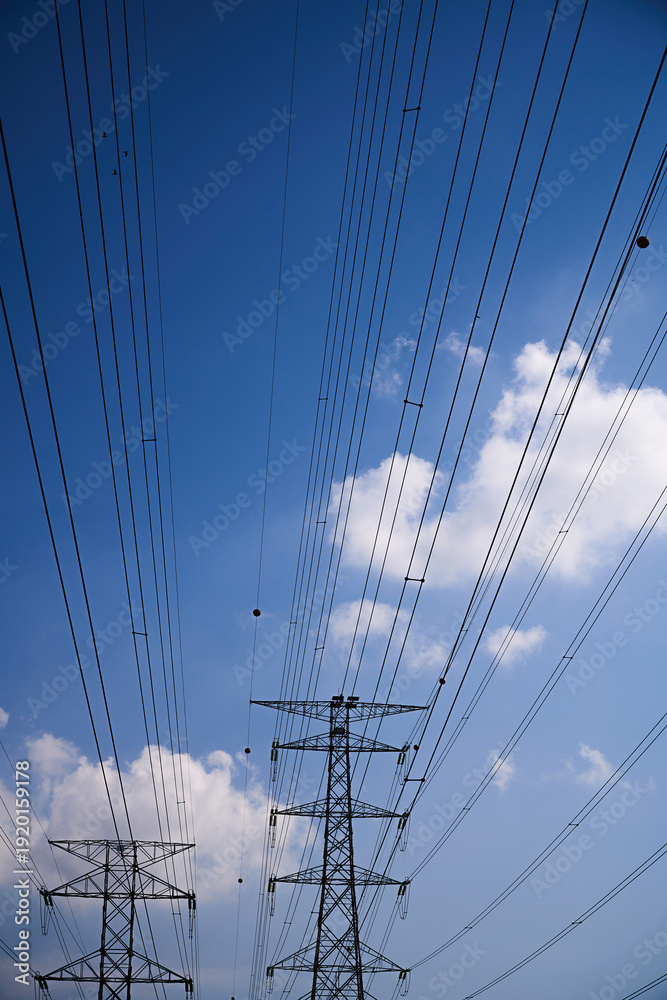 Obraz premium High Voltage Transmission Towers Against Blue Sky