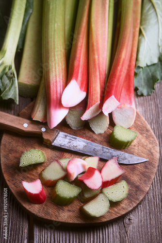 Canvastavla Rhubarb chunks scattered on wooden board with kitchen knife, natural light food styling