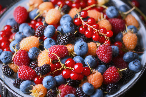 Close up of mixed summer berries in bowl, shallow depth of field. Fresh organic assortment, vibrant fruit texture
