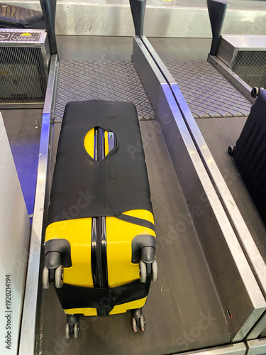 Billede på lærred Black and yellow hard-shell suitcase with wheels placed on a baggage conveyor be