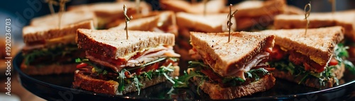 Multiple layered sandwiches cut into triangles are presented on a dark platter