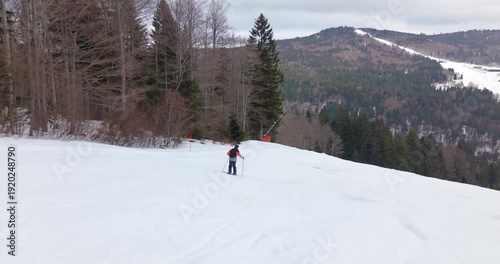 Drone follow shot of skier carving down snowy alpine slope