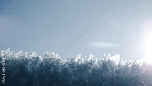 Billede på lærred Macro shot of sparkling ice crystals and frost against a clear blue sky with bri