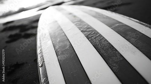 Surfboard Stripes: An artistic monochrome image features a surfboard resting on the shore, its bold stripes adding a graphical element to the coastal landscape, evokes a sense of adventure, freedom.