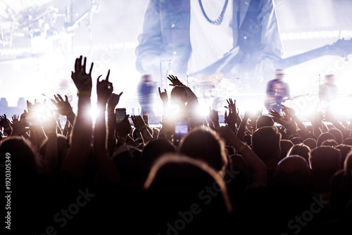 Large Audience with Raised Hands Silhouetted Against a Bright Concert Stage