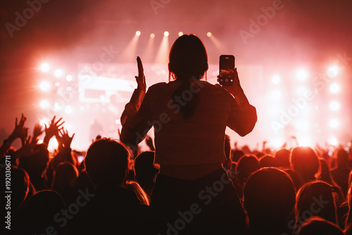 Cuadro en lienzo Girl on shoulders recording concert in red lighting background