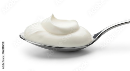 Close-up of a dollop of fresh, creamy white yogurt or sour cream on a silver spoon, isolated on a clean white background.