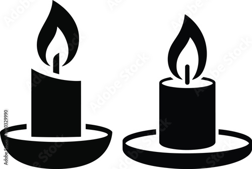 Two black candles with lit wicks placed side by side on round bases