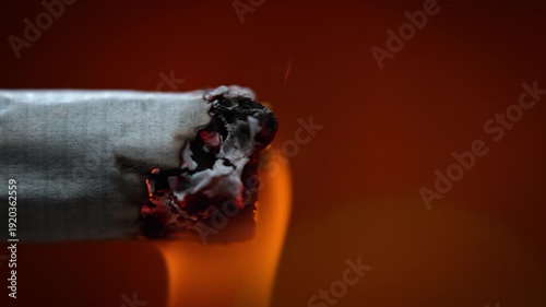 Lighting a Cigarette with Fire in Macro and Slow Motion, Smoke Causing Cancer is Inhaled, Tobacco Smolders and Burns to Ash, Red Background