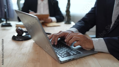 Two lawyers discuss legal documents at a desk, with a scale of justice and gavel symbolizing law, authority, and professional legal consultation in a modern office.