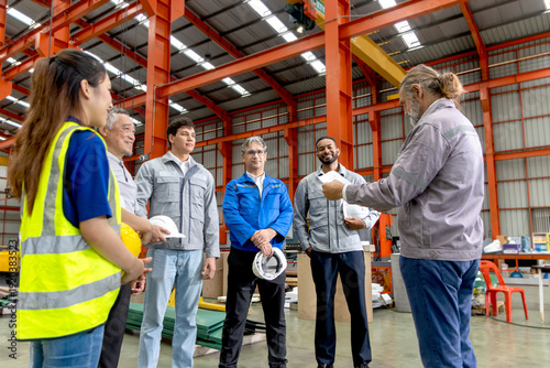 Supervisor of diverse engineers briefing his team before working in manufacturing factory. Leader giving a briefing to team in industrial site. Worker manager conducting a site meeting in a factory.