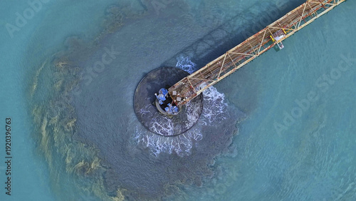 Aerial view of a rusty pier stretching into the turquoise waters, a stark contrast of industrial decay against the serene sea, Bullhead City, Arizona, United States.