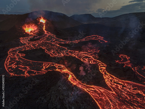 Aerial view of molten lava flowing through the dark volcanic landscape, a fiery river carving its path near Grindavik, Grindavikurbaer, Iceland.
