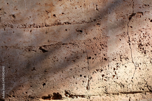 Textured rammed earth wall with natural light and shadows creating depth and contrast