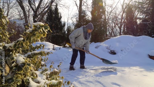 Portrait of an elderly woman with a snow shovel in winter. An old woman removes snow with a shovel in winter.