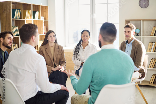 People group of adults in team training meeting. A coach leads discussion with participants in a bright circle, sharing ideas and building skills. Concept of unity and open communication.