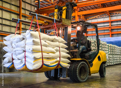 Bild auf Leinwand Forklift handling large white jumbo bags of refined sugar in an industrial warehouse for logistics and export
